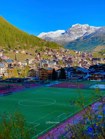 Village and sports field beneath snowy peaks