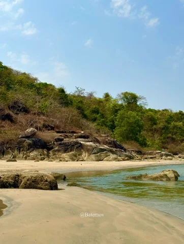 Sandy cove beneath a rocky wooded headland