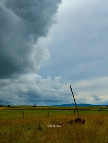 Towering storm cloud above flat farmland