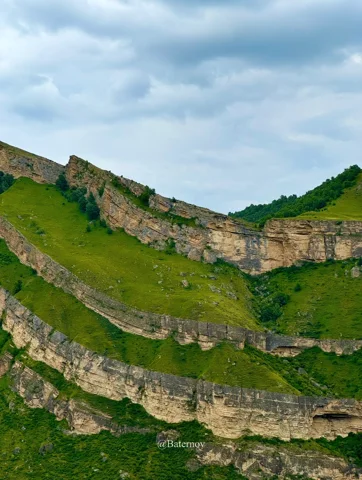 Layered cliffs tracing the folds of a green hillside