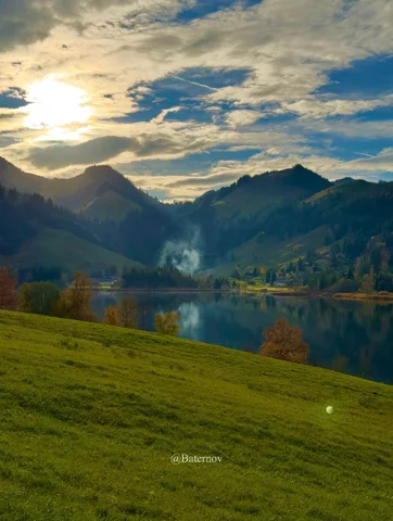 Evening sunlight above a lake and green pasture