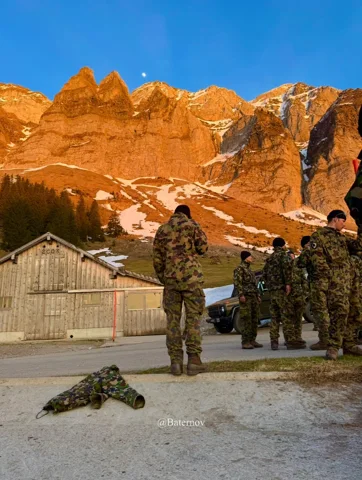 Uniformed soldiers beneath orange-lit mountain cliffs