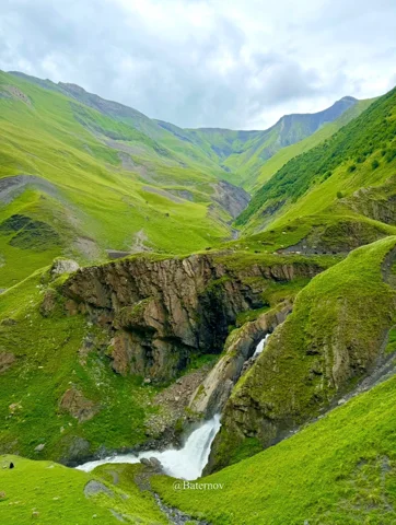 Waterfall cutting through a green mountain valley
