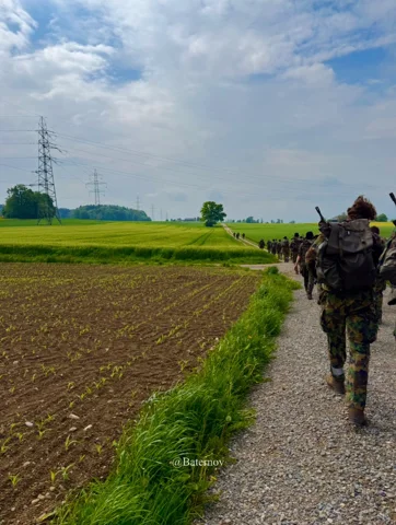 Soldiers walking along a track beside cultivated fields