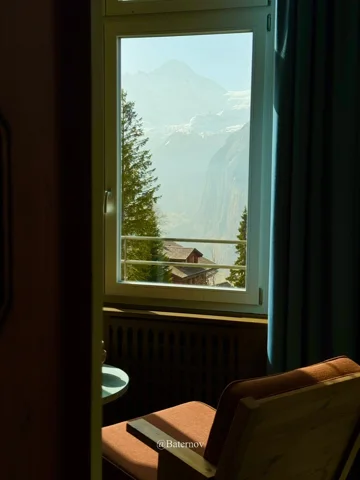 Mountain view through a window beside an armchair
