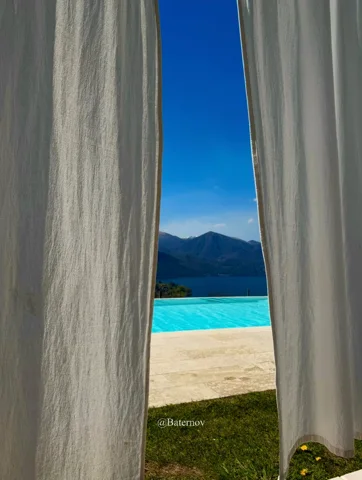 White curtains opening onto a pool and distant mountains