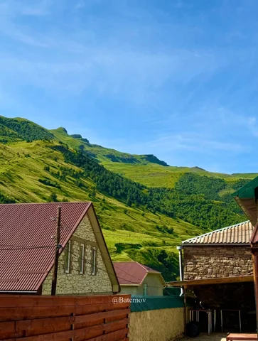Village rooftops beneath green mountain slopes