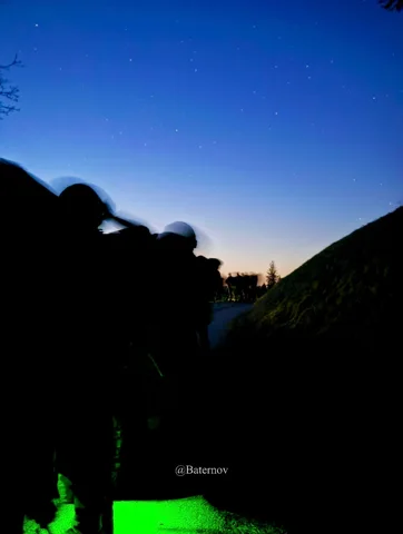 Silhouettes outdoors beneath a darkening blue sky