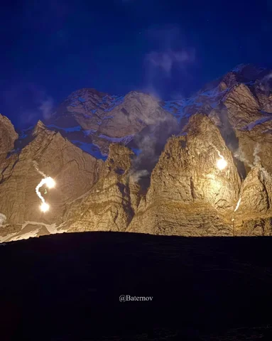 Bright lights against mountain cliffs at night