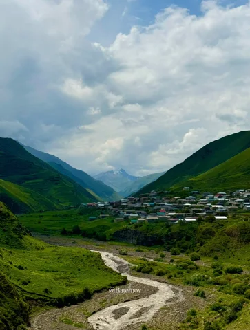 Village and winding riverbed in a green mountain valley