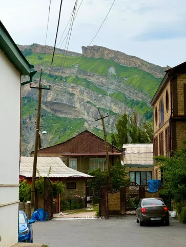 Village street beneath layered mountain cliffs