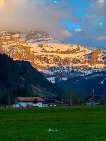 Evening light on snowy cliffs above a village