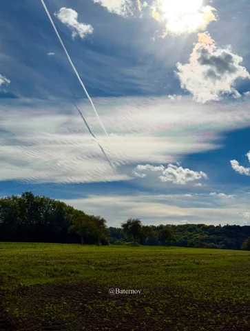 Sunlight and cloud bands above open farmland