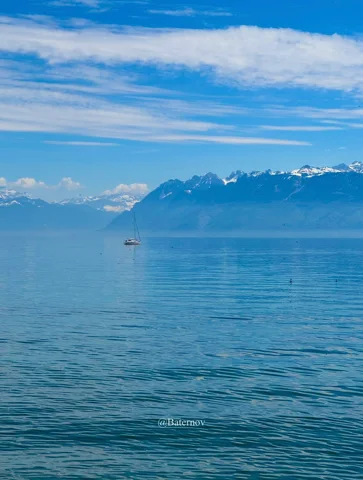 Calm blue lake facing distant mountains