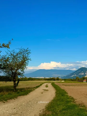 Dirt track crossing fields toward distant mountains