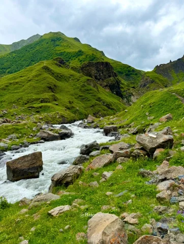 Rocky stream flowing through green mountain slopes