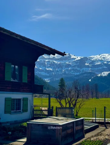 Chalet and water trough overlooking snowy mountains