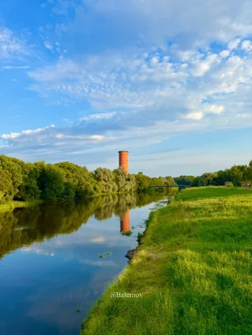 River reflecting a distant tower and cloudy sky