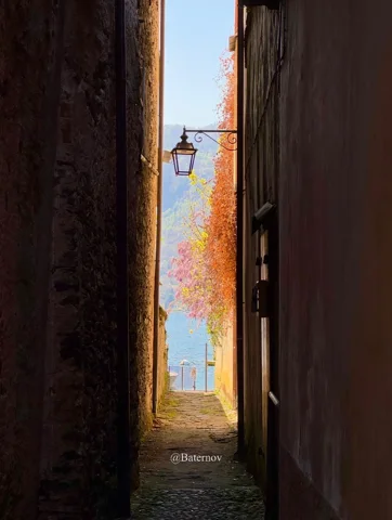 Narrow shaded passage opening onto a bright village lane