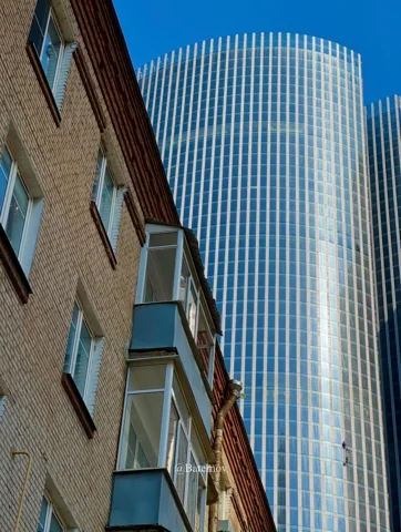 Modern glass tower rising behind an older building