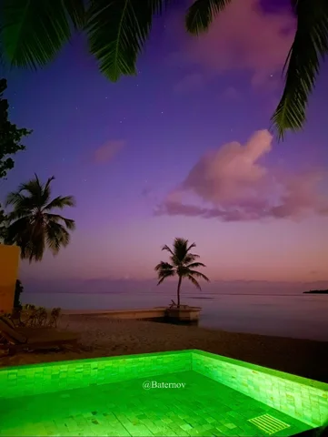 Illuminated pool facing the sea beneath an evening sky