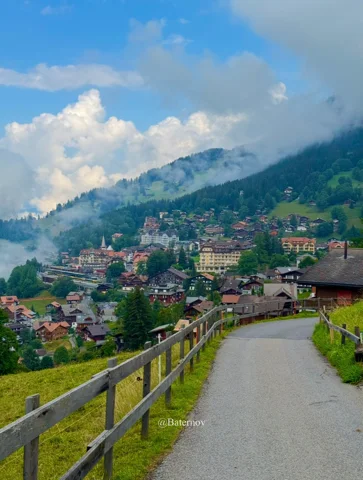 Paved path descending toward a mountain village
