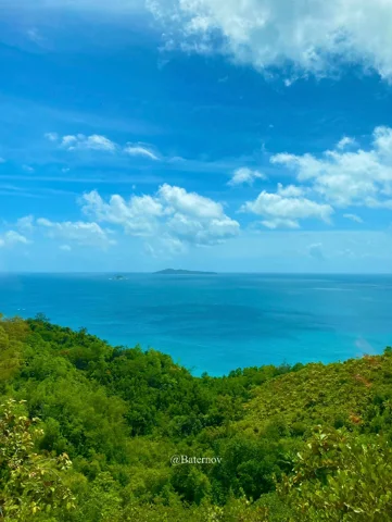 Turquoise sea beyond a green tropical hillside