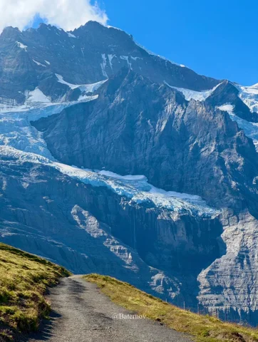 Mountain path facing steep snow-streaked peaks