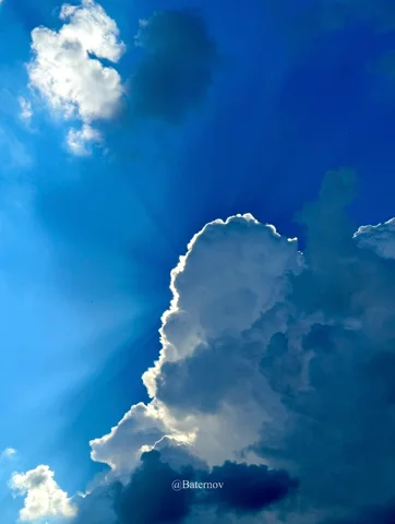 Sunlight outlining tall white clouds against deep blue sky