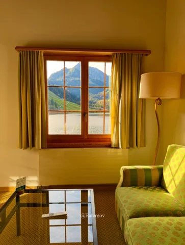 Mountain view through a curtained window in a sitting room