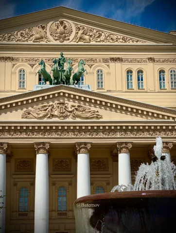 Columned theatre facade behind a fountain