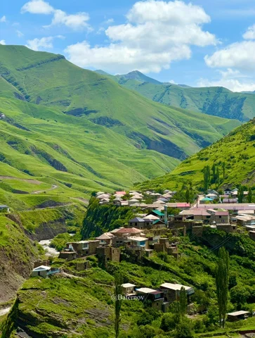 Houses clustered on a green mountain slope