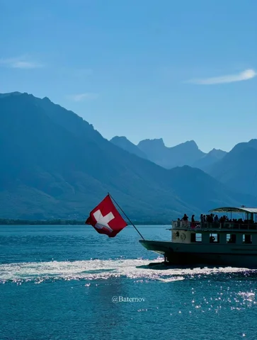 Passenger boat with a Swiss flag crossing a mountain lake