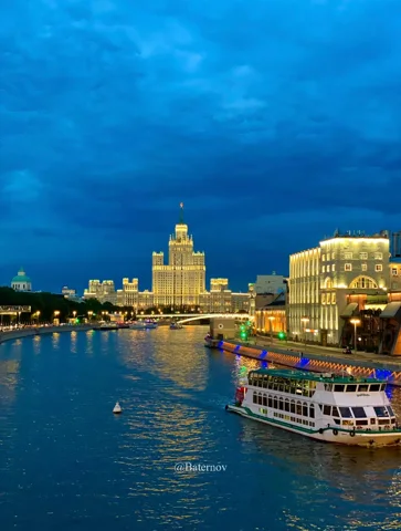 Illuminated riverside buildings beneath a dark blue sky