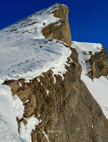 Snow-covered rocky summit against a deep blue sky