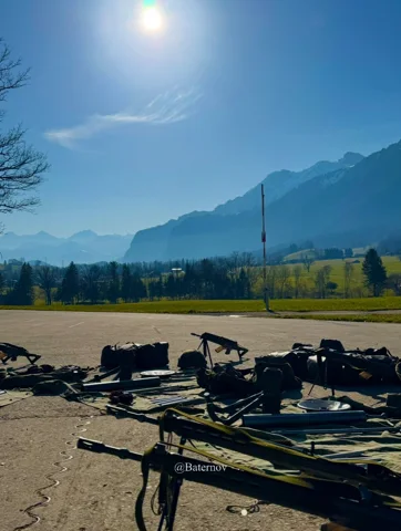 Military equipment on paved ground beneath mountains