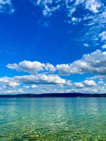 Clear shallow lake water beneath scattered clouds