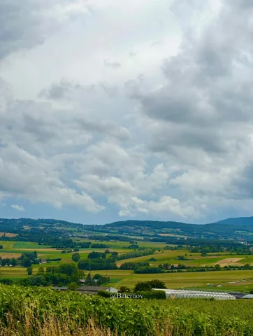 Rolling farmland and scattered buildings beneath clouds