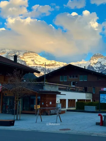 Village square beneath sunlit snowy peaks
