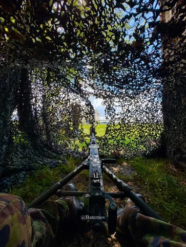 View from beneath camouflage netting toward trees