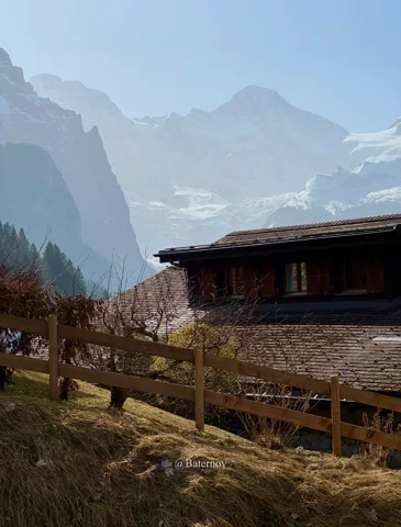 Wooden building beneath misty mountain peaks