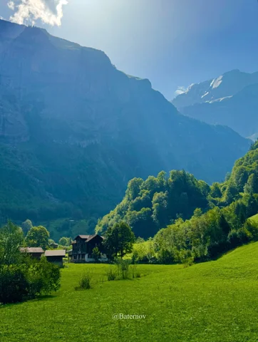Meadow and houses beneath a steep mountain wall