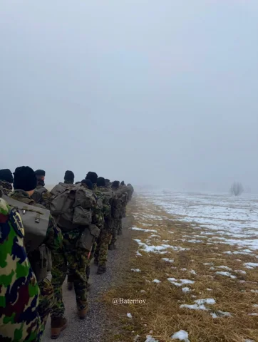 Soldiers walking across a misty snow-dusted landscape