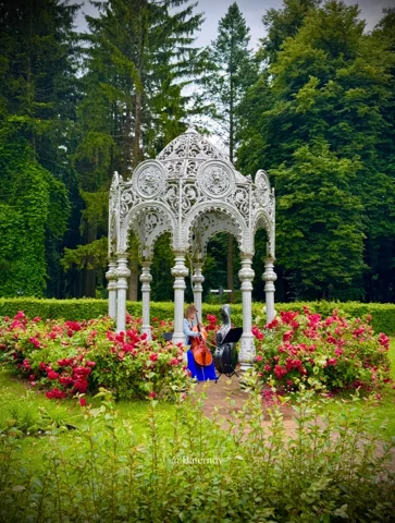 White ornamental pavilion surrounded by flowers and trees