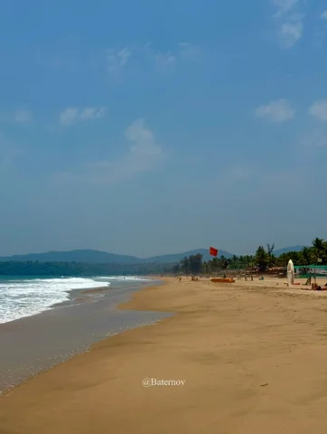 Broad sandy beach with waves and distant beach huts