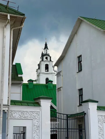 White buildings with green roofs and a church tower