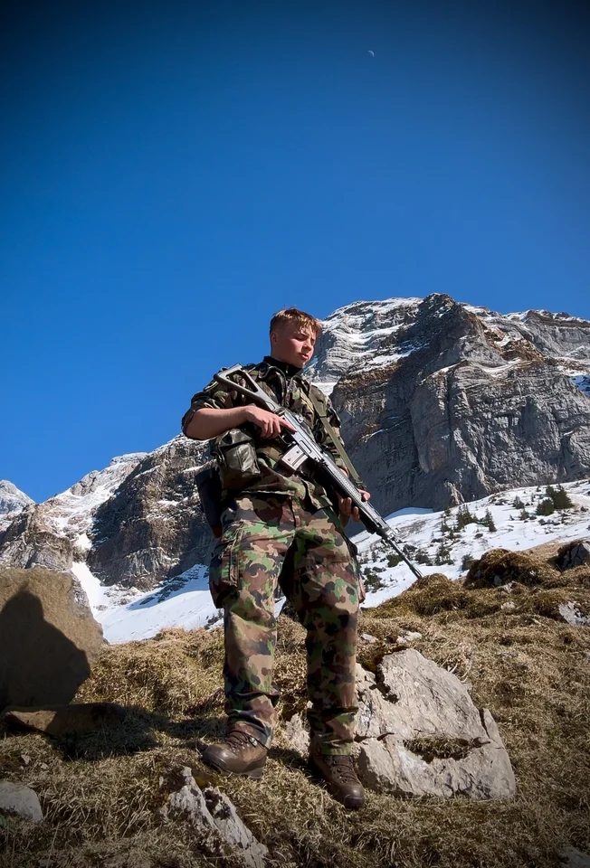 Brandon in camouflage clothing on a rocky mountain slope.