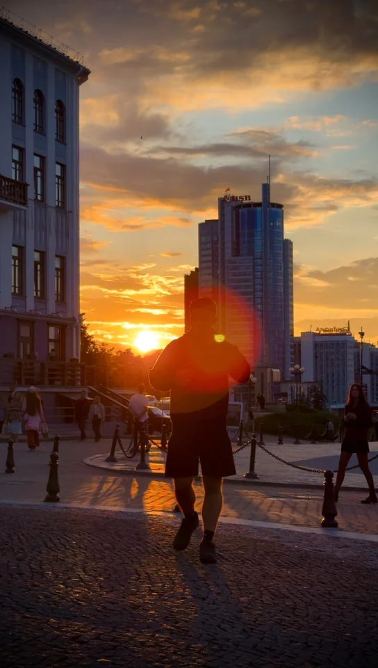 Brandon walking along a cobbled street with the setting sun behind him.
