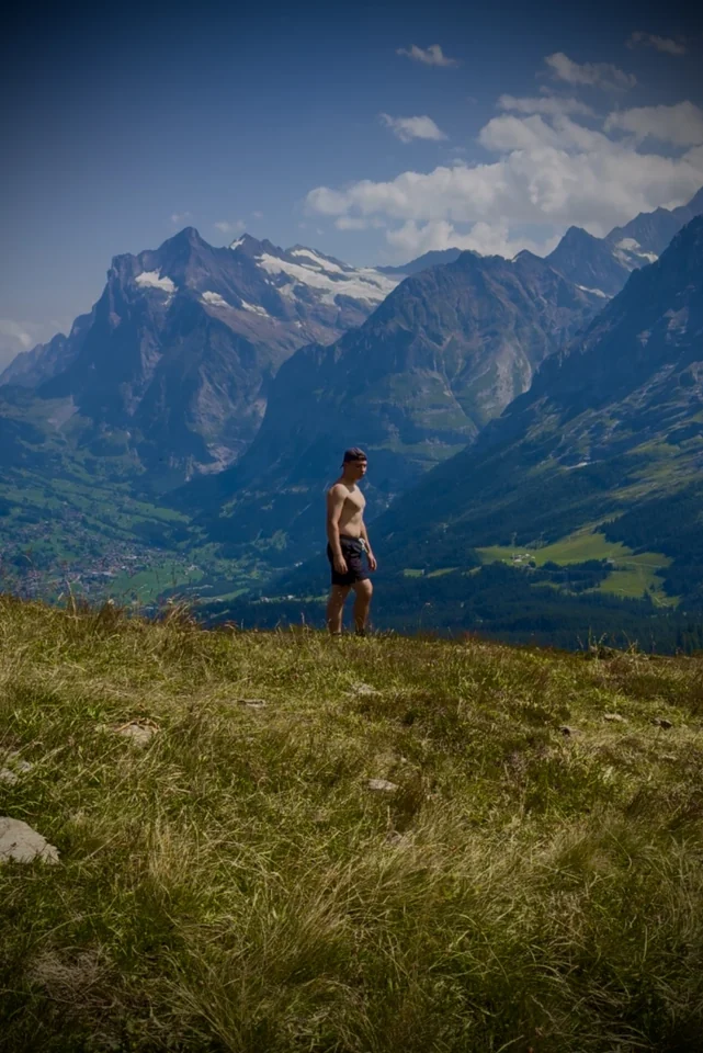 Brandon standing in an alpine meadow overlooking a mountain valley.